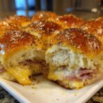 Close-up of gooey Hawaiian Roll Ham and Cheese Sliders topped with poppy seeds and a shiny glaze.