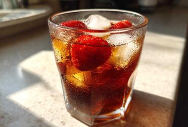 Close-up of a glass filled with Iced Strawberry Lemon Tea, ice cubes, and fresh strawberries.