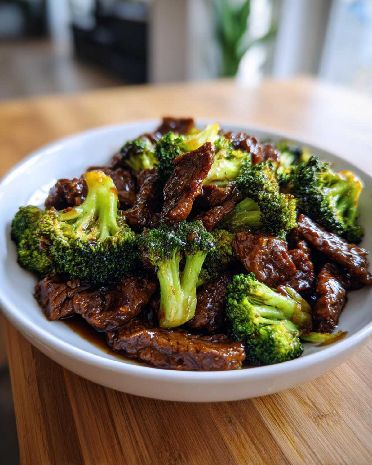 A white bowl filled with glistening Instant Pot Beef and Broccoli, featuring tender beef slices and bright green florets.