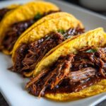 Close-up of crispy tacos filled with rich, shredded Instant Pot Beef Barbacoa.