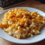 A close-up of creamy, cheesy Instant Pot Mac and Cheese topped with melted cheddar cheese on a white plate.