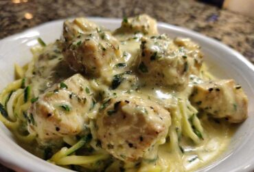 Close-up of Keto Chicken Alfredo featuring chunks of chicken breast smothered in creamy sauce over zucchini noodles.