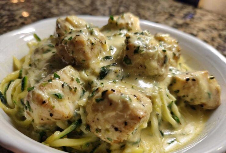 Close-up of Keto Chicken Alfredo featuring chunks of chicken breast smothered in creamy sauce over zucchini noodles.