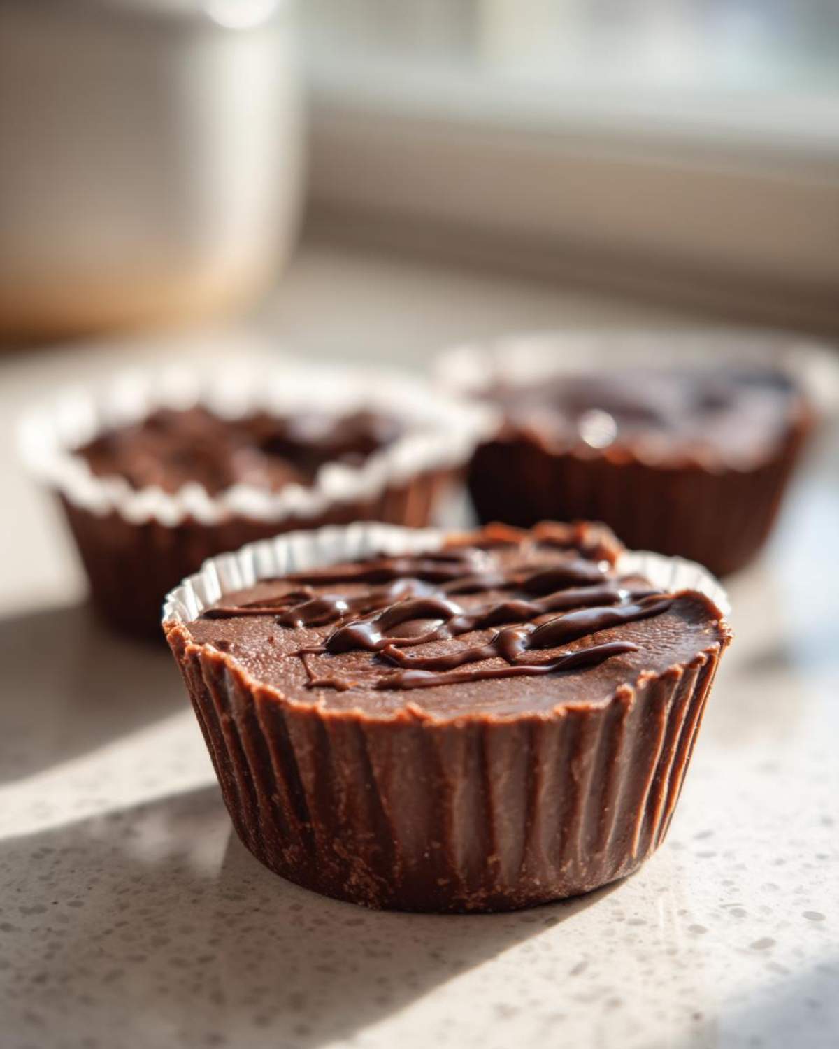 A close-up of a rich, dark chocolate Keto Chocolate Peanut Butter Fat Bomb drizzled with extra chocolate.