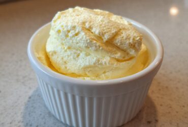 Close-up of light yellow, airy Keto Lemon Cheesecake Mousse served in a small white fluted ramekin.