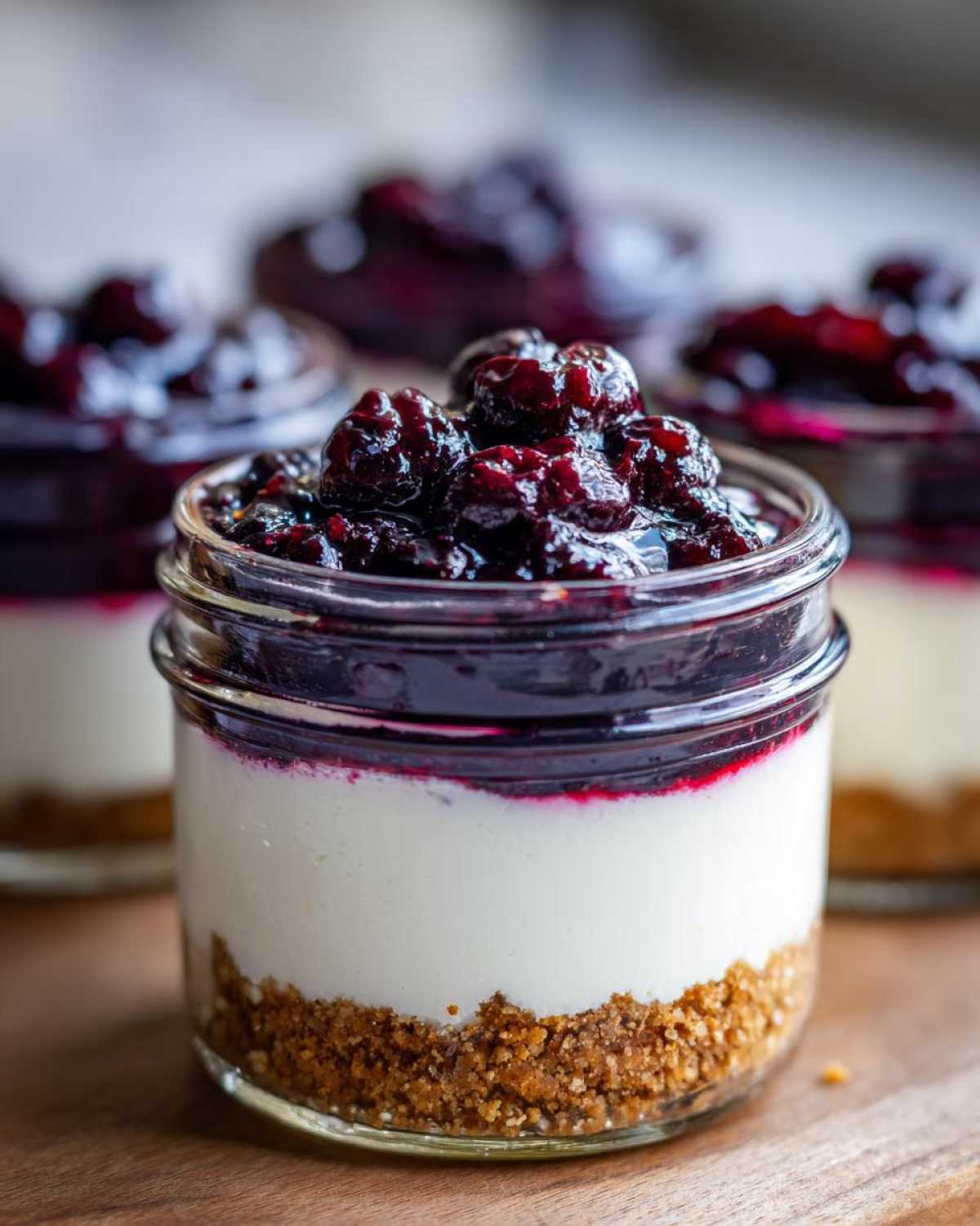Close-up of a single serving of Lemon Blueberry Cheesecake Jars showing graham cracker crust, creamy filling, and blueberry topping.