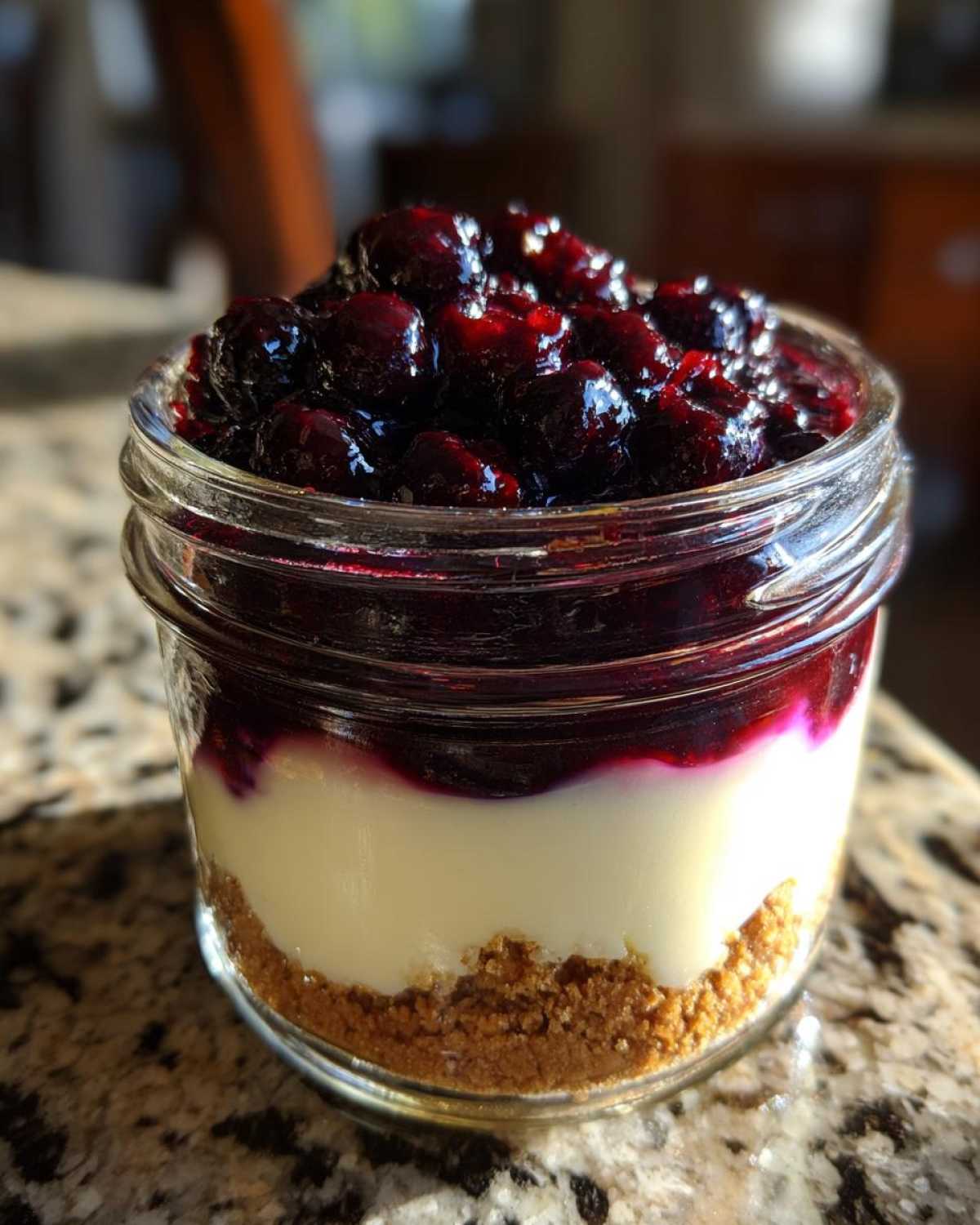Close-up of a single serving Lemon Blueberry Cheesecake Jars showing graham cracker crust, creamy filling, and blueberry topping.