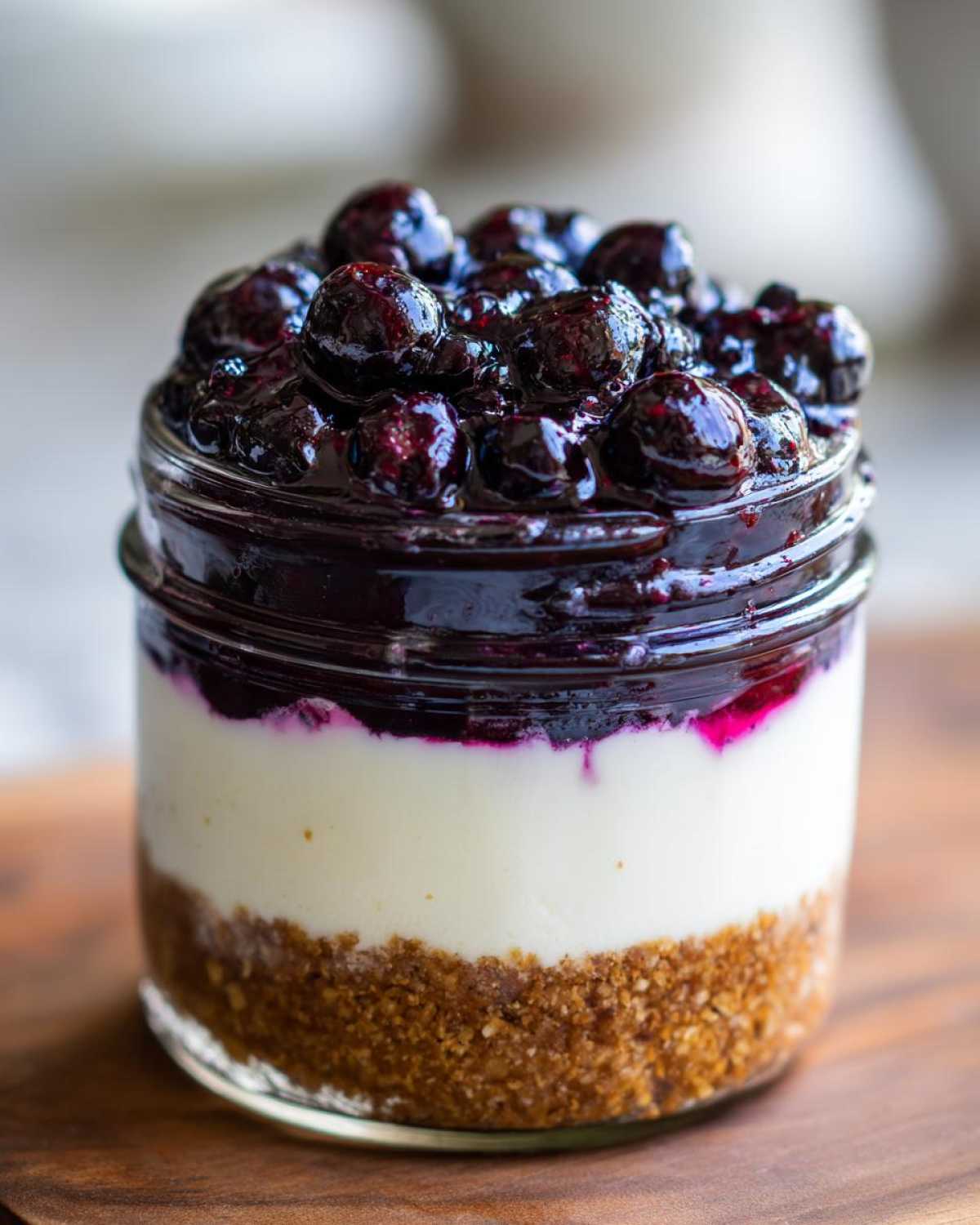 Close-up of a single serving Lemon Blueberry Cheesecake Jars with graham cracker crust, creamy filling, and blueberry topping.