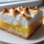A close-up of a single serving of Lemon Meringue Pie Bars with a thick, toasted meringue topping.