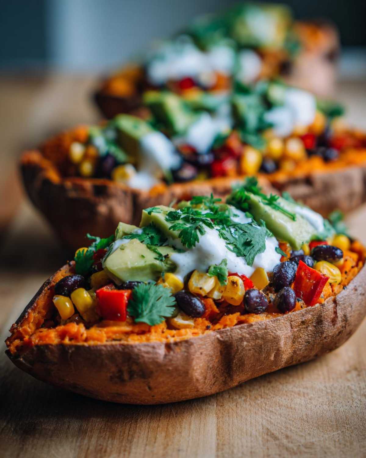Close-up of a Loaded Veggie Stuffed Sweet Potato topped with black beans, corn, avocado, and sour cream.