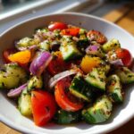 Close-up of a vibrant Mediterranean Cucumber Tomato Salad with red onion and herbs in a white bowl.