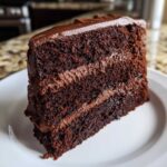 Close-up of a moist, layered slice of Gluten-Free Chocolate Cake covered in rich chocolate frosting.