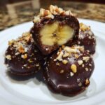 Close-up of No-Bake Chocolate Covered Banana Bites, one cut in half showing banana center and nut topping.