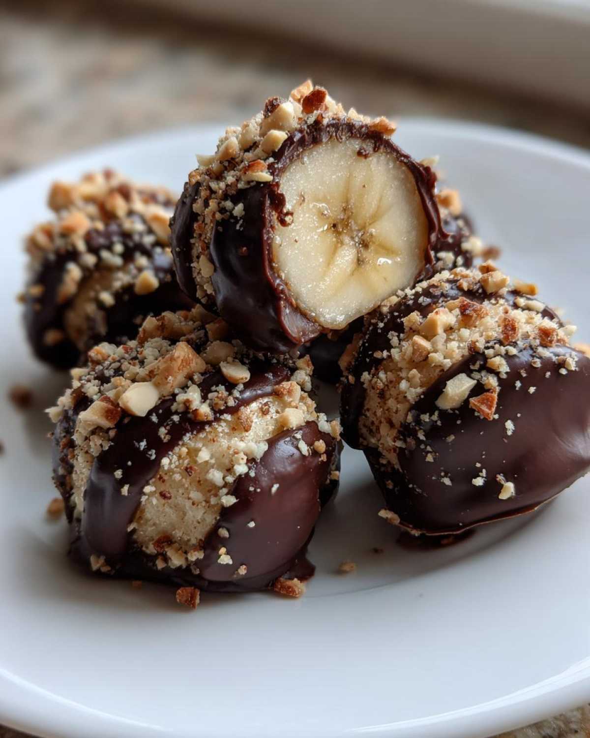 Close-up of No-Bake Chocolate Covered Banana Bites dipped in chocolate and topped with chopped nuts.