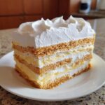 A layered slice of No-Bake Lemon Icebox Cake showing graham crackers, lemon filling, and whipped cream.