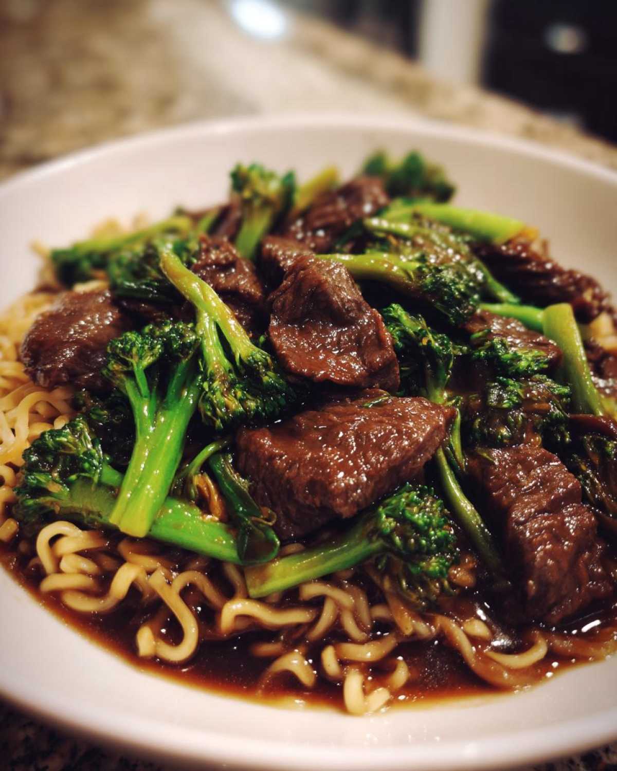 Close-up of savory One-Pot Beef and Broccoli Ramen Noodles served in a white bowl with rich sauce.