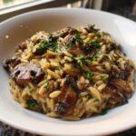 Close-up of One-Pot Creamy Mushroom Orzo topped with sautéed mushrooms and fresh parsley.