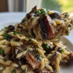 A spoonful of creamy One-Pot Creamy Mushroom Orzo, rich with brown mushrooms and parsley garnish.