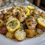 Plated Sheet Pan Lemon Pepper Chicken and Potatoes garnished with fresh lemon slices and parsley.