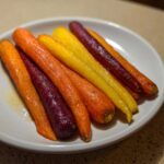 Close-up of glossy, roasted Sheet Pan Roasted Rainbow Carrots with Honey on a white plate.