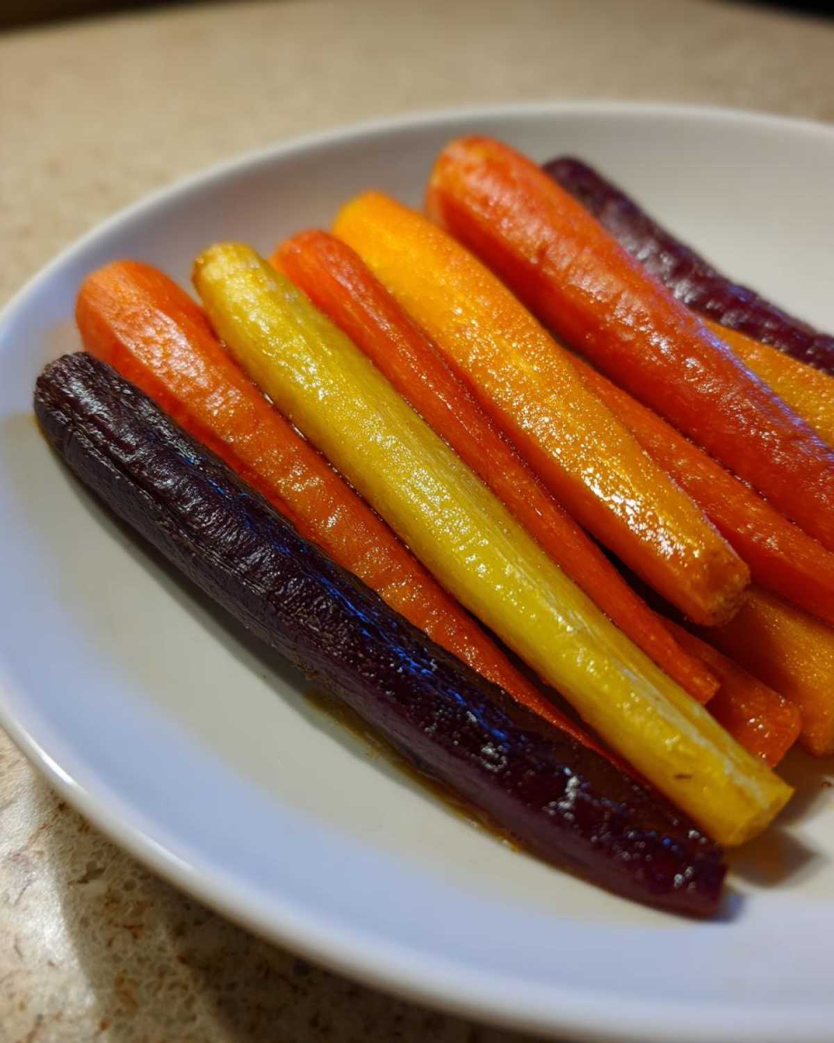 Close-up of glazed Sheet Pan Roasted Rainbow Carrots with Honey, showing purple, yellow, and orange carrots.
