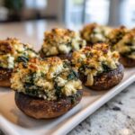 Close-up of baked Spinach and Feta Stuffed Mushrooms with a golden, cheesy topping served on a white platter.