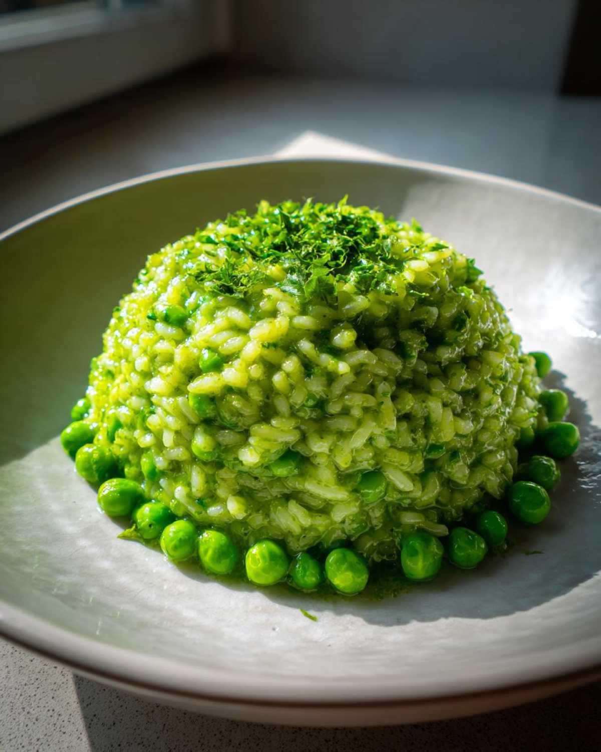 A perfectly molded mound of bright green Spring Pea and Mint Risotto topped with fresh herbs.