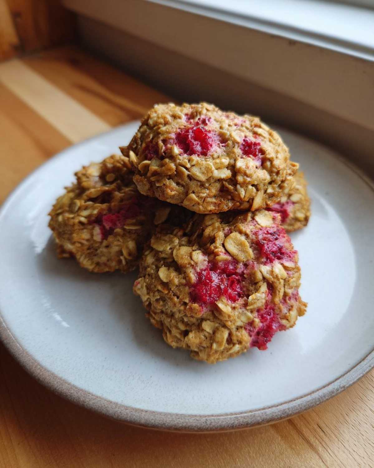 A stack of three golden Strawberry Oatmeal Breakfast Cookies featuring visible oats and bright red baked-in fruit.