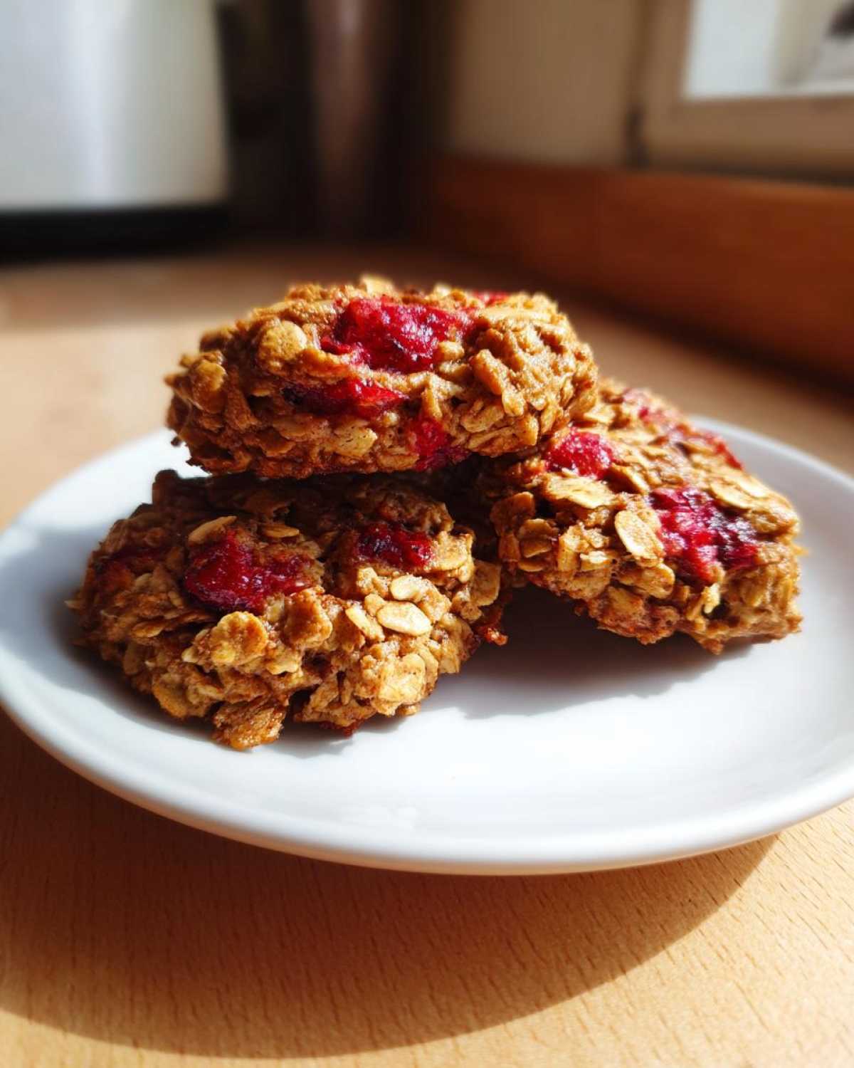 Close-up of three chewy Strawberry Oatmeal Breakfast Cookies stacked on a small white plate.
