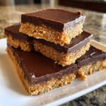 A stack of rich, no-bake Peanut Butter Bars featuring a thick base and smooth chocolate topping.