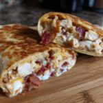 Two halves of a golden-brown Air Fryer Crispy Chicken Bacon Ranch Wrap showing the creamy filling of chicken, bacon, and ranch sauce.