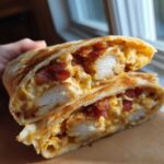 A close-up of Air Fryer Crispy Chicken Bacon Ranch Wraps cut in half, showing crispy chicken, bacon, and creamy ranch filling.