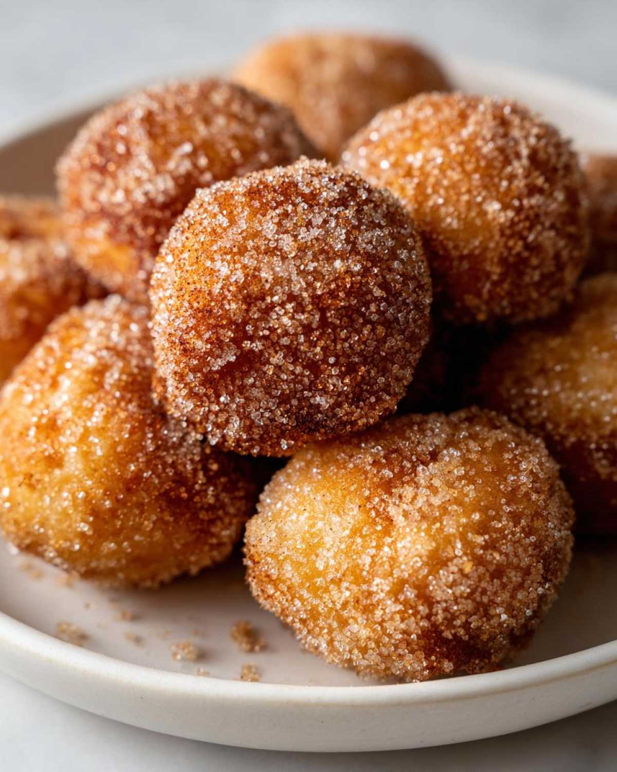 A close-up stack of golden brown Air Fryer Crispy Cinnamon Sugar Pretzel Bites heavily coated in sparkling cinnamon sugar.