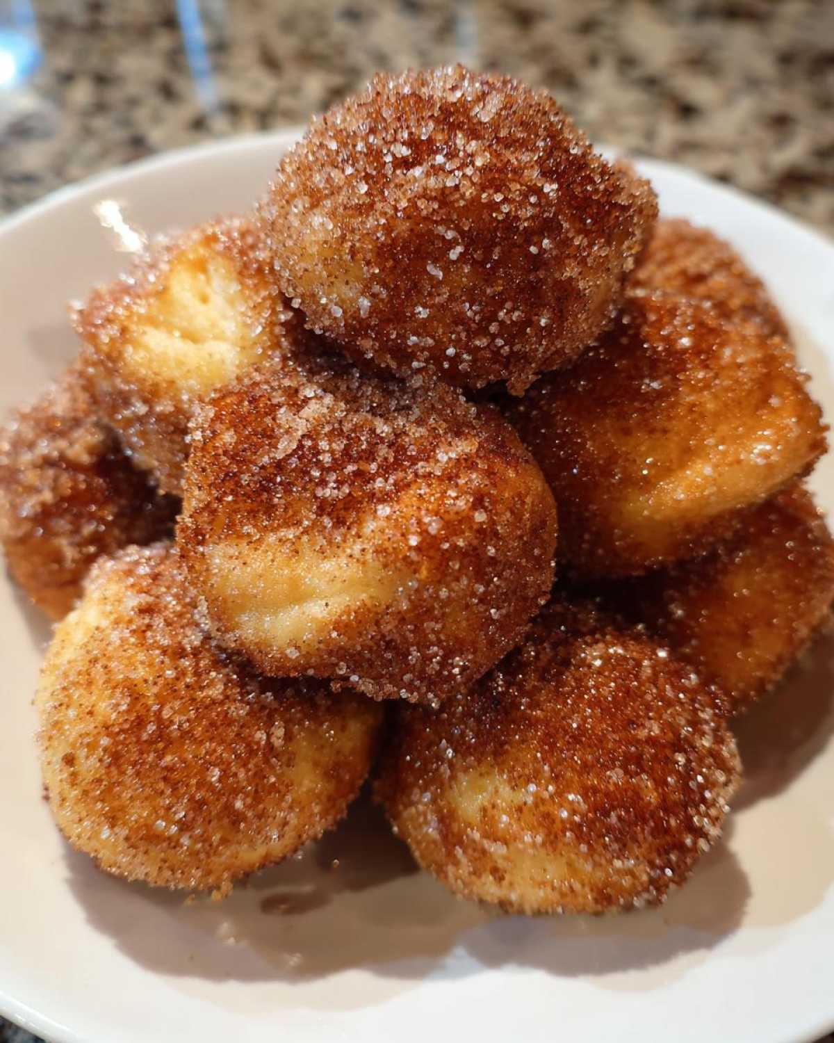 Close-up of a pile of golden brown Air Fryer Crispy Cinnamon Sugar Pretzel Bites coated heavily in sparkling cinnamon sugar.
