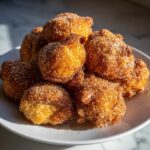 A close-up of a pile of golden brown Air Fryer Crispy Cinnamon Sugar Pretzel Bites coated heavily in sparkling cinnamon sugar.