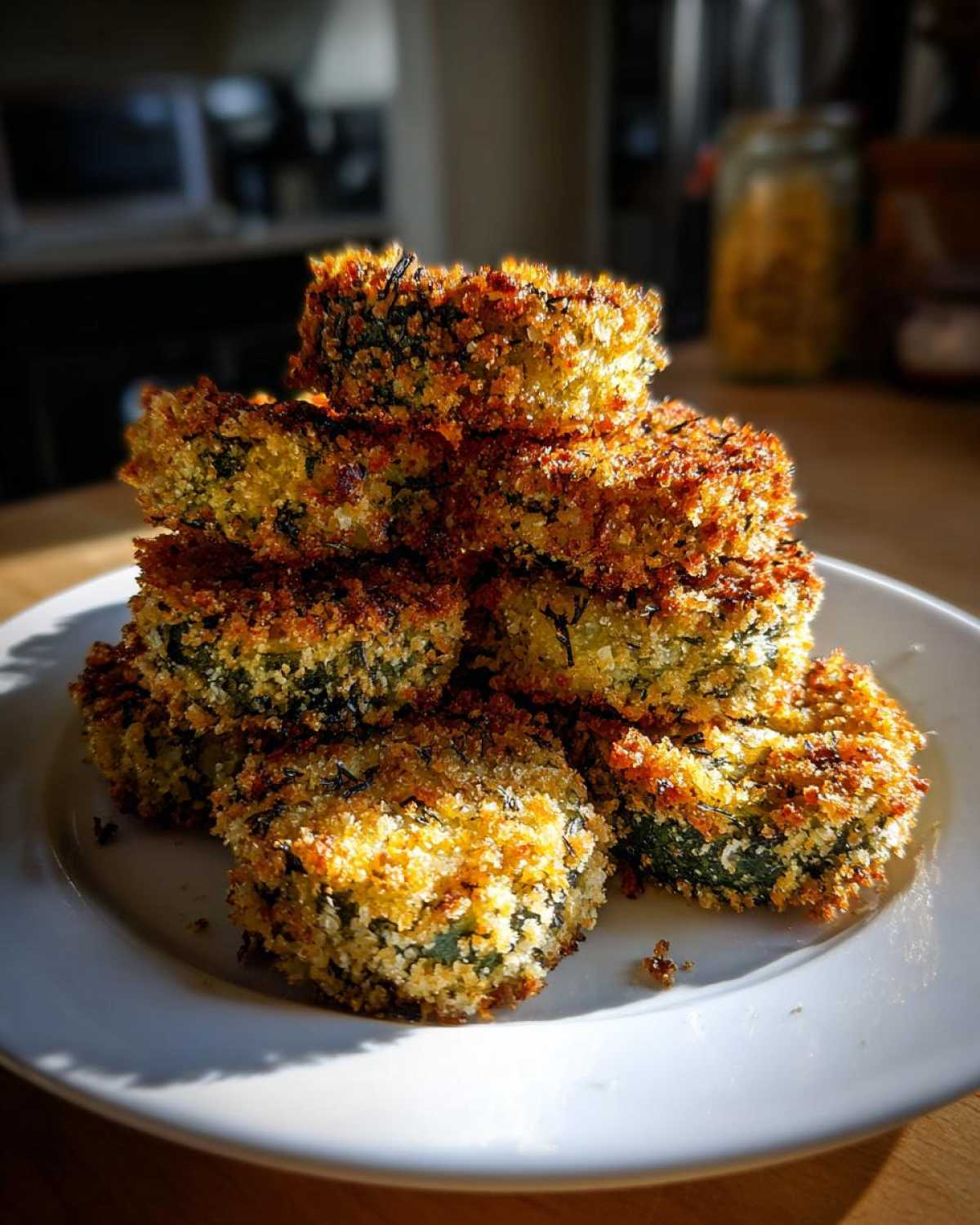 A stack of golden brown, crispy Air Fryer Crispy Garlic Dill Pickles slices piled high on a white plate.