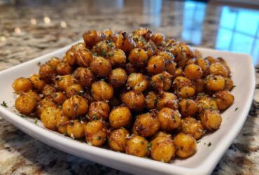 A close-up of golden brown Air Fryer Crispy Garlic Herb Chickpeas seasoned with herbs, piled high in a white square bowl.