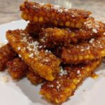 A stack of golden brown Air Fryer Crispy Parmesan Garlic Corn Ribs dusted with white grated cheese.