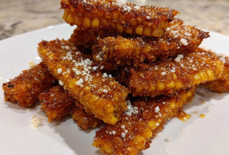 A stack of golden brown Air Fryer Crispy Parmesan Garlic Corn Ribs dusted with white grated cheese.