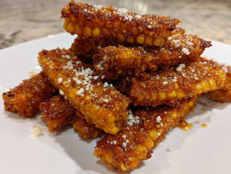 A stack of golden brown Air Fryer Crispy Parmesan Garlic Corn Ribs dusted with white grated cheese.