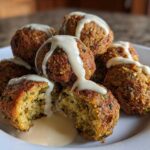 Close-up of golden brown Air Fryer Herb Falafel Balls stacked on a white plate, drizzled generously with creamy tahini sauce.