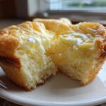 A close-up view of a Cheesecake Muffins half, showing the moist, fluffy interior and creamy cheesecake topping.