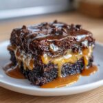 A rich, moist slice of Chocolate Caramel Dump Cake dripping with gooey caramel and chocolate sauce.