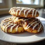 A stack of three delicious Cinnamon Roll Cookies drizzled with white icing, one cookie has a bite taken out.
