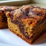 Two squares of rich, golden Cinnamon Swirl Snickerdoodle Blondies topped with coarse sugar crystals.