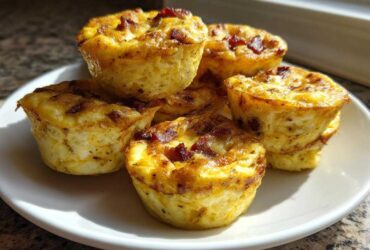 A stack of golden-brown Copycat Café-Style Bacon Gruyere Egg Bites served on a white plate.