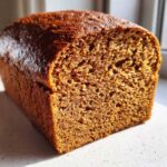 A close-up, cross-section view of a freshly baked loaf of Copycat Dark Brown Honey Wheat Bread showing its dense, moist crumb.