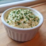 A small white ramekin filled with thick Copycat Pizza Garlic Parmesan Dip Sauce, topped with fresh parsley.