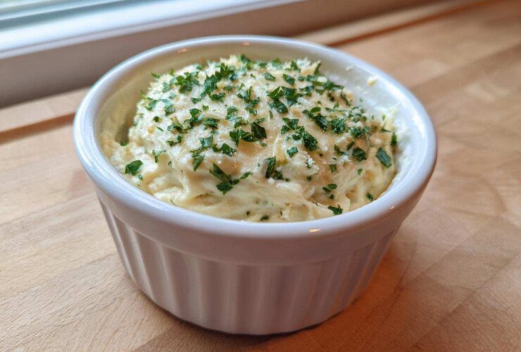 A small white ramekin filled with thick Copycat Pizza Garlic Parmesan Dip Sauce, topped with fresh parsley.