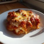 A single serving of Creamy Roasted Garlic Tomato Gnocchi Bake, topped with melted, browned cheese.